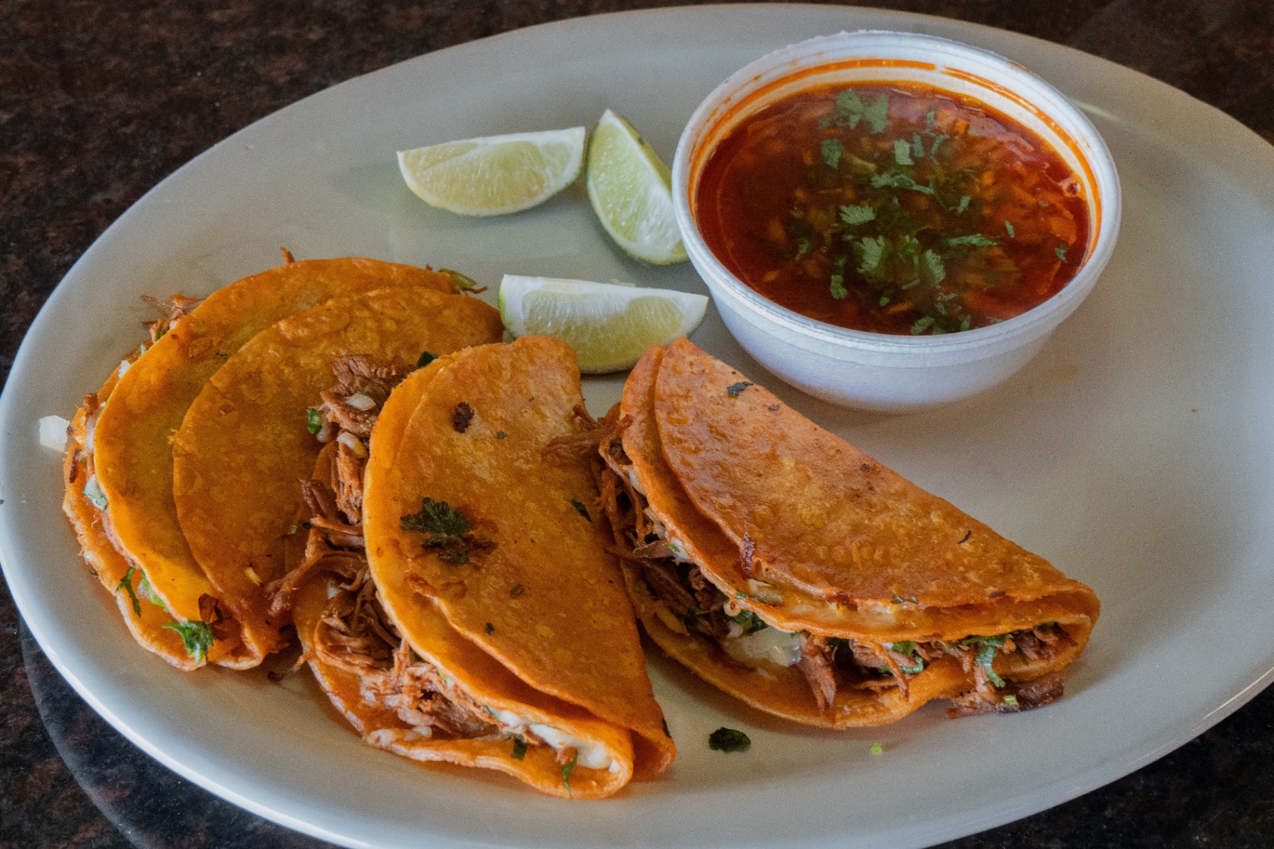Birria tacos with consommé and lime