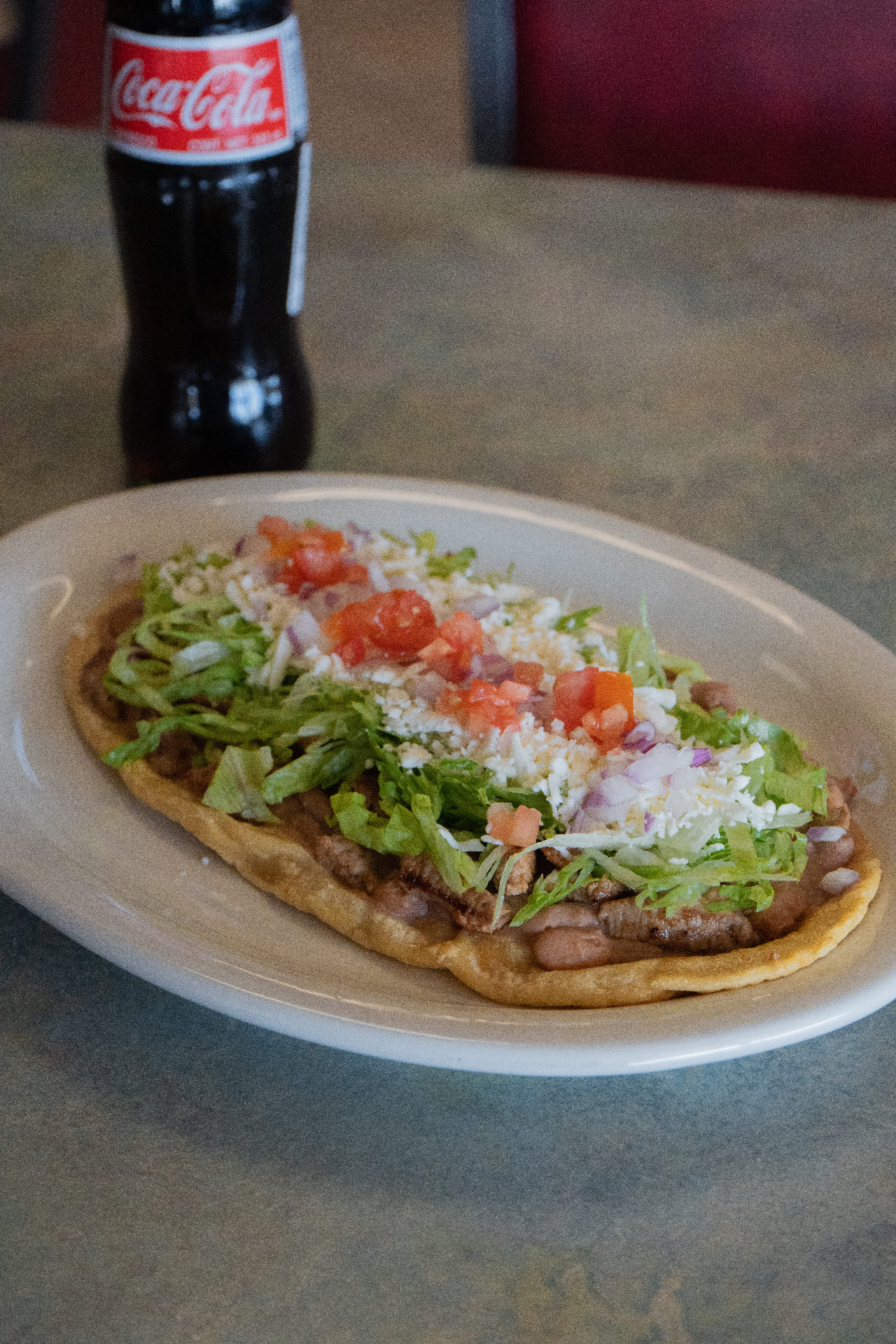 Mexican huarache with refried beans, steak, lettuce, tomato, and queso fresco
